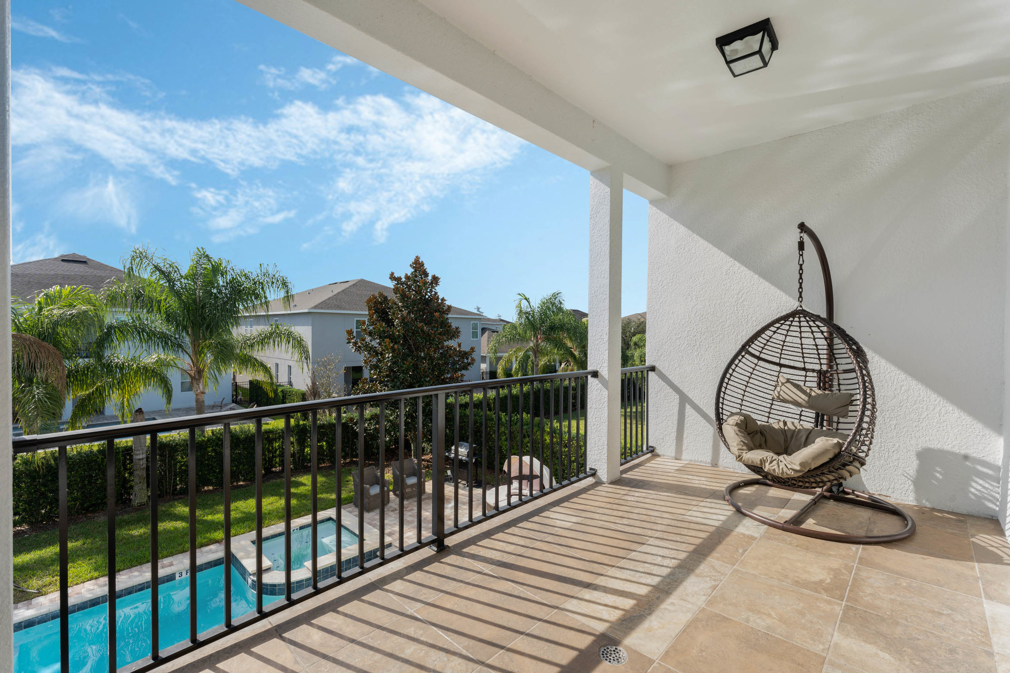 upstairs balcony with nest hanging chair overlooking pool